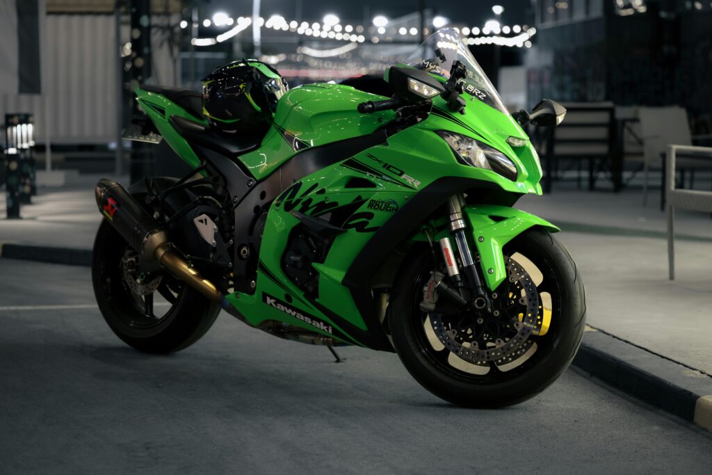 A sleek green motorcycle parked under urban night lights, showcasing modern design.